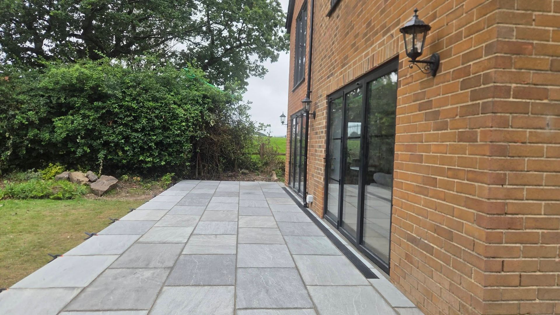 Raised grey patio beside a brick home in Horsforth