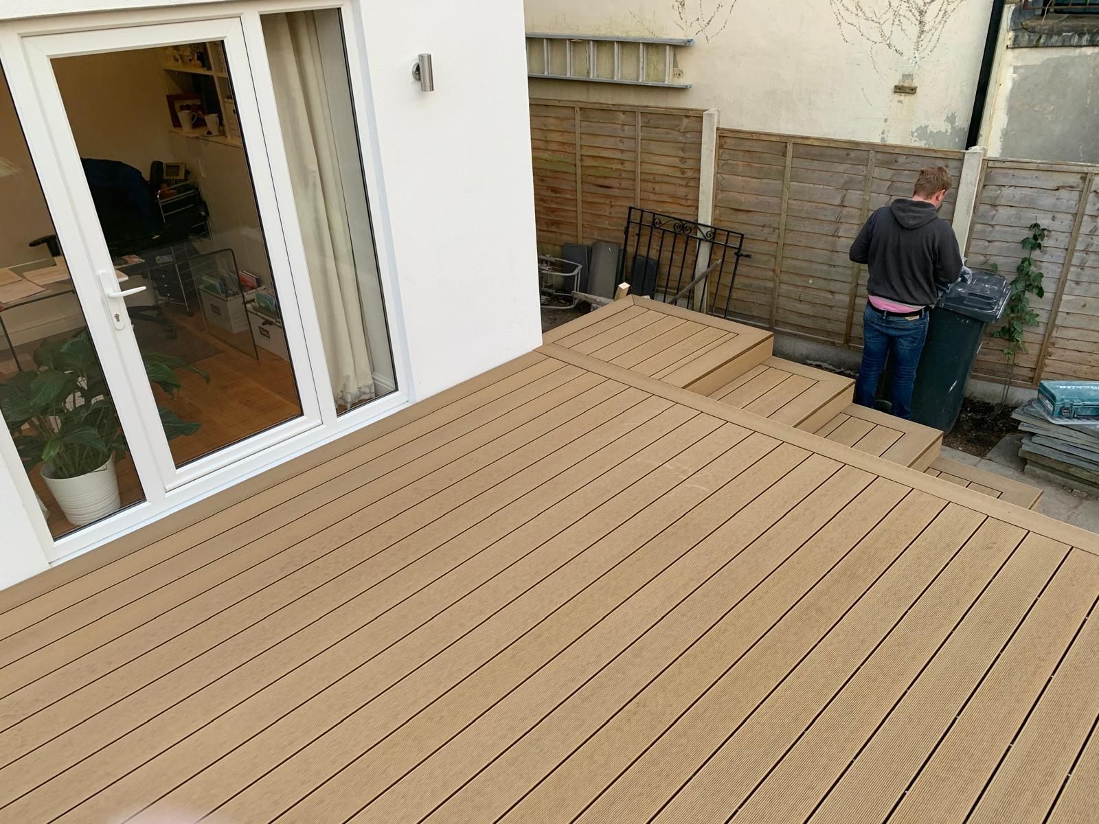 Beige composite decking and matching steps beside a white house