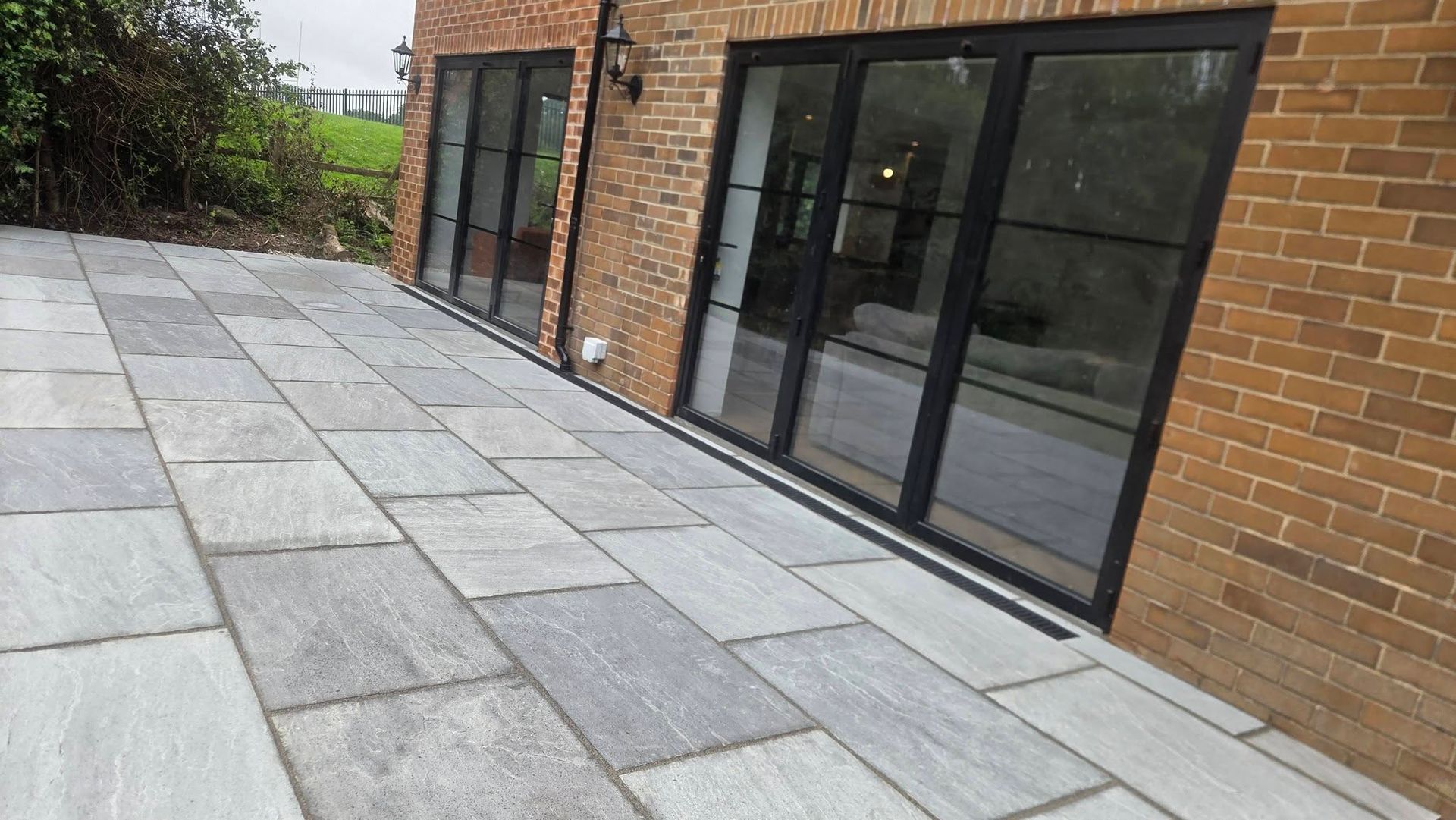 Raised grey patio beside a brick home in Horsforth