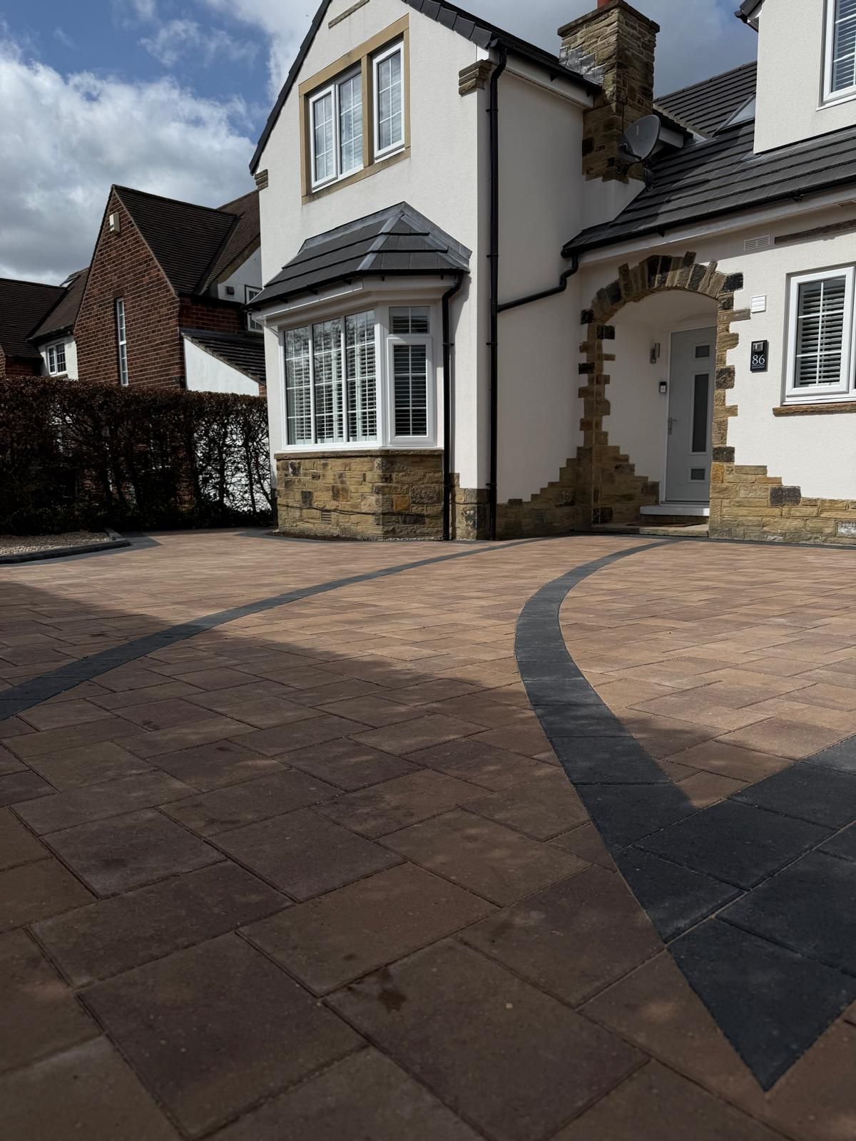 Curved block paving driveway with dark contrasting border and decorative layout