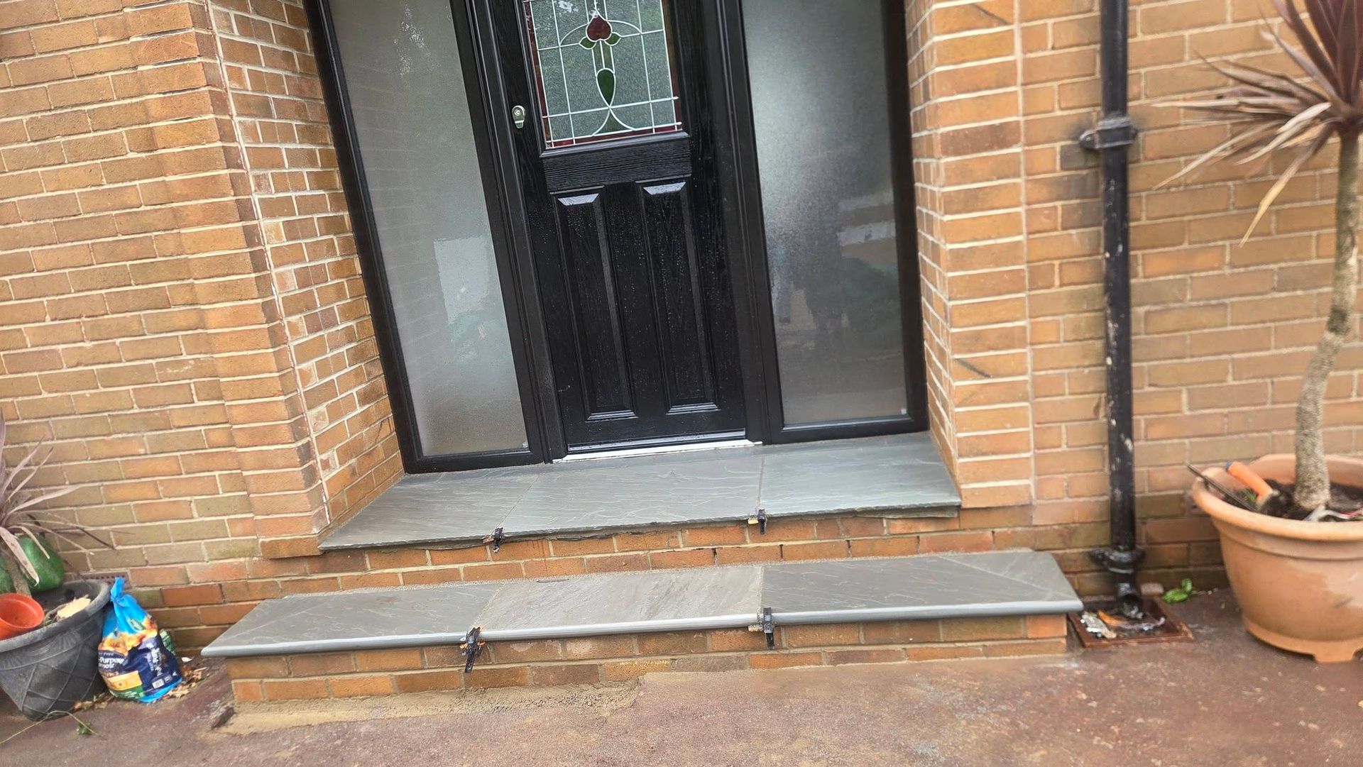 Raised grey patio beside a brick home in Horsforth