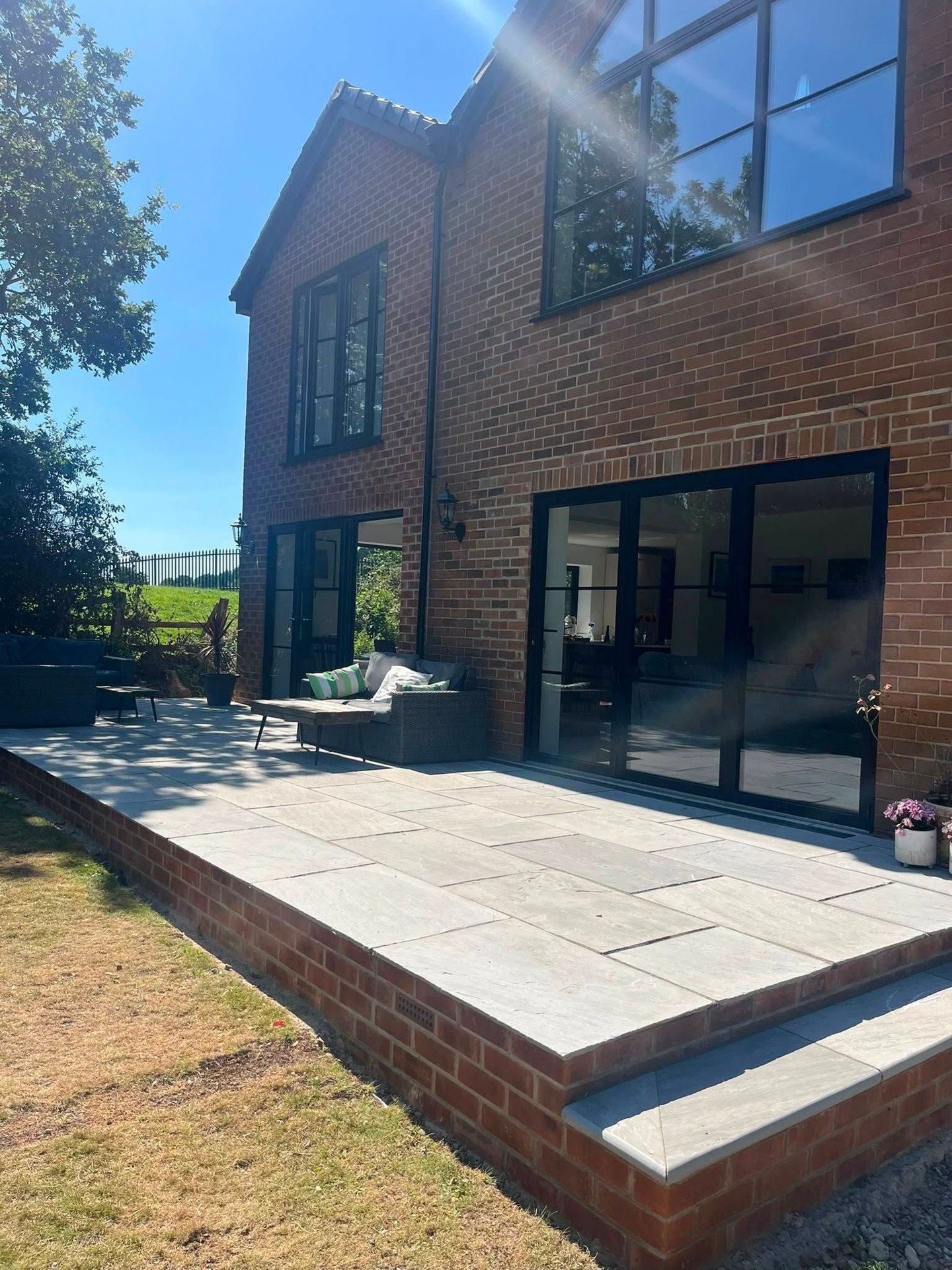 Raised grey patio beside a brick home in Horsforth